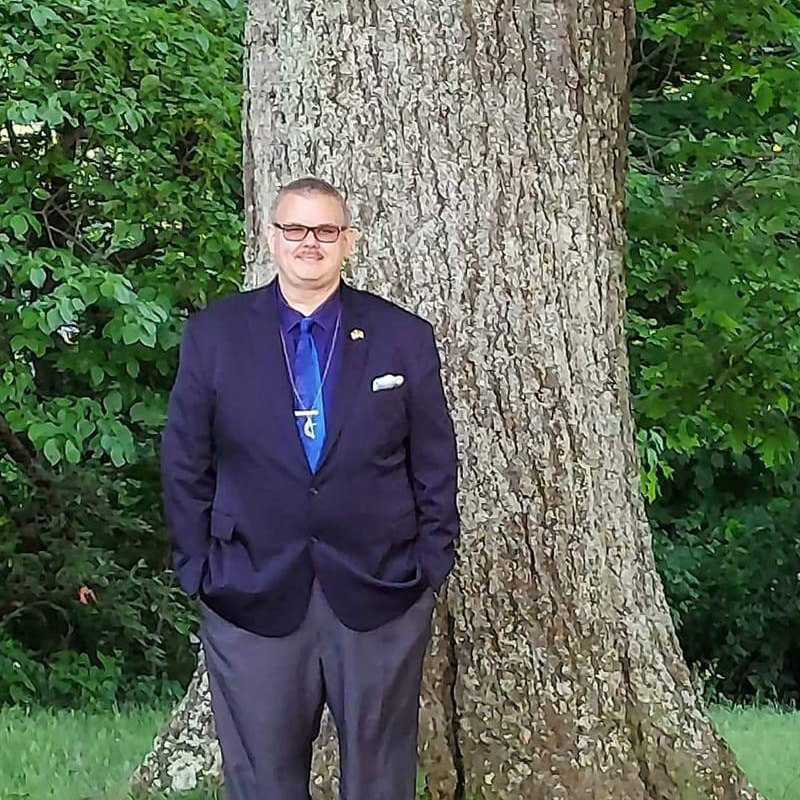 Ed Clemons, Jr. standing in front of a tree with his hands in his pocket